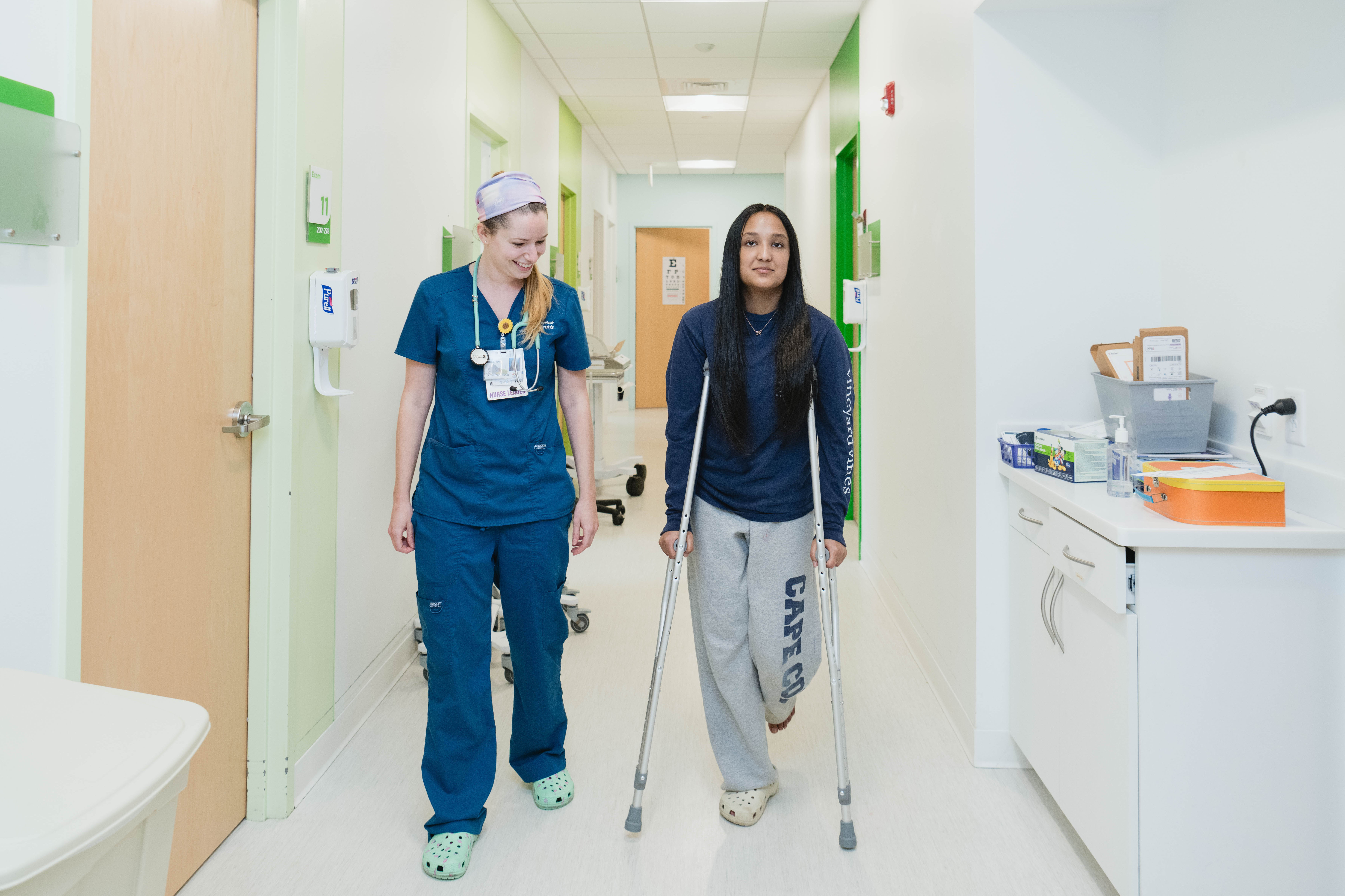 teenage girl walks the hallway on crutches at urgent care
