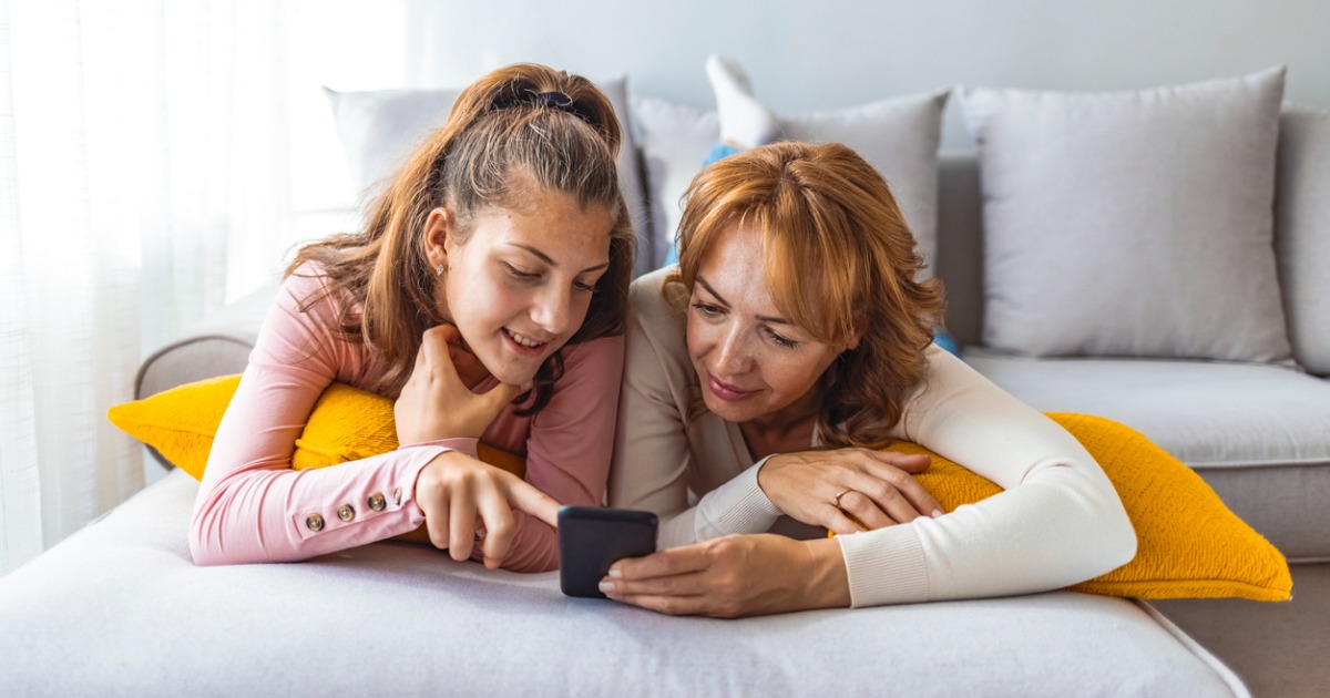 A mother and daughter look at a phone