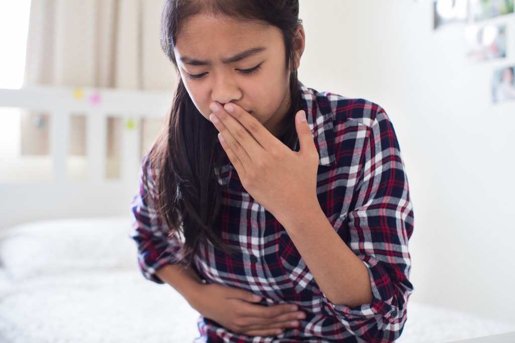 Young girl sitting on bed feeling nauseous