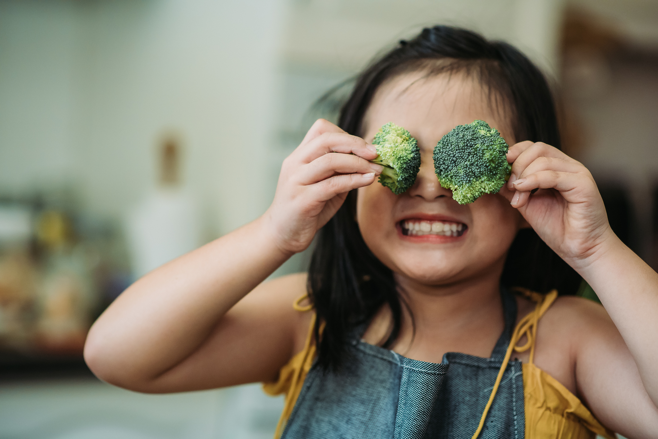 A child holding broccoli up to their face.