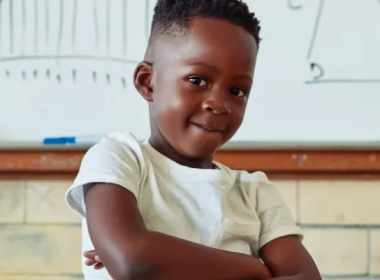 Boy crossing his arms in front of a whiteboard