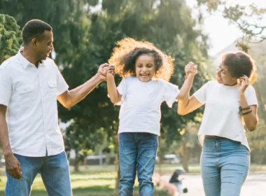 Girl swinging in-between Mom and Dad's hands