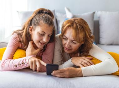 A mother and daughter look at a phone