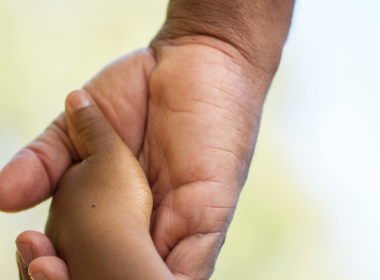 Child holding hands with an adult