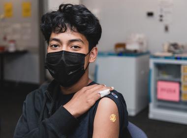 A teen shows off where they got their COVID vaccine