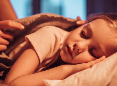 Young girl being tucked into bed