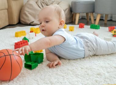 Cute baby boy playing with toys on carpet