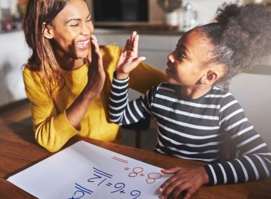 Mom and school-aged daughter high-fiving during math assignment