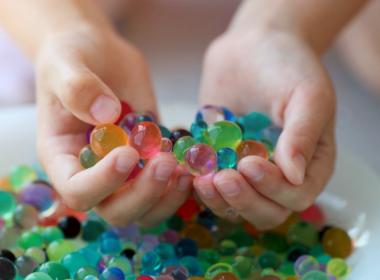 Water beads in hand over bowl. Dangerous toy.