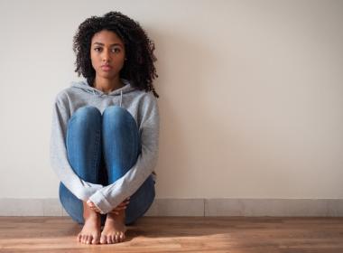 Young girl sits on floor, feeling sad and depressed.