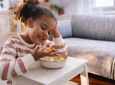 School age child eating a bowl of fruit