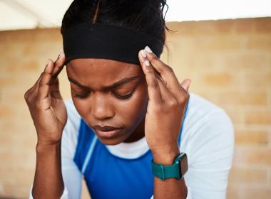 Female athlete injured, holding head, closing eyes