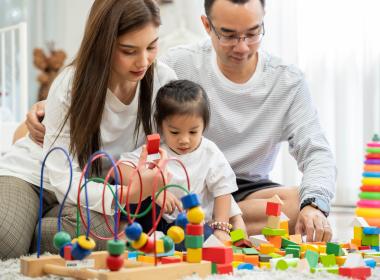 Parents building blocks with child. 