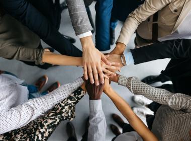 Circle of people with hands in the center on top of each other