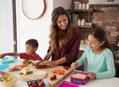 Mom with two school-aged kids in kitchen food prepping