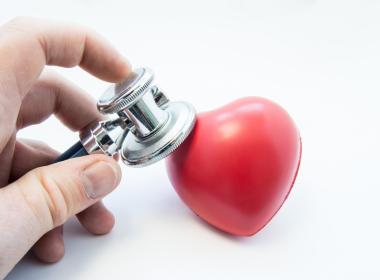 Doctor holding stethoscope in his hand, examines heart shape for presence of diseases of cardiovascular system. Photo for use in cardiology, cardiac surgery, diagnosis and treatment of heart disease