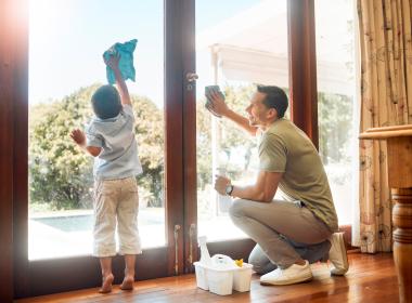 A father and son cleaning a window together.