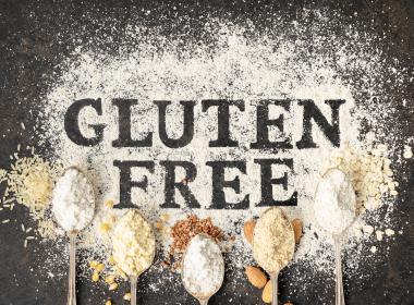 Gluten Free written on table of flour surrounded by spoons