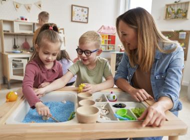 Mother playing on sensory table with two young children
