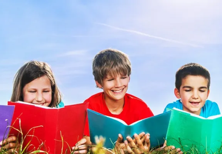 Kids reading books laying the grass