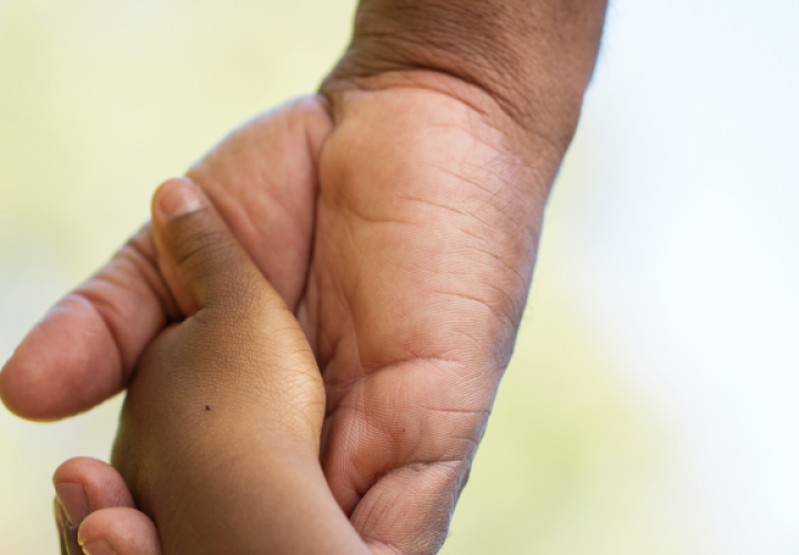 Child holding hands with an adult