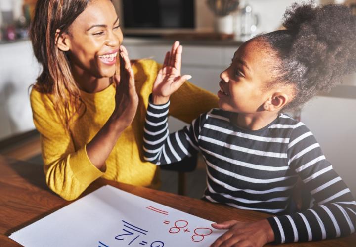 Mom and school-aged daughter high-fiving during math assignment