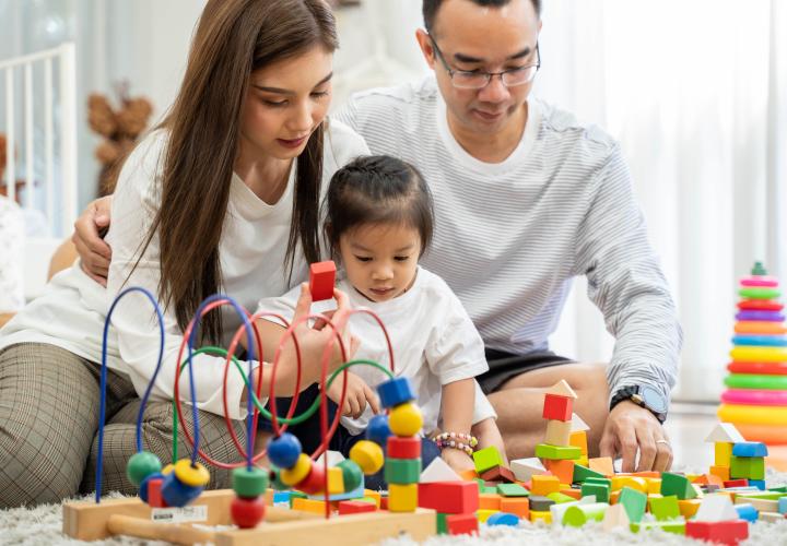 Parents building blocks with child. 