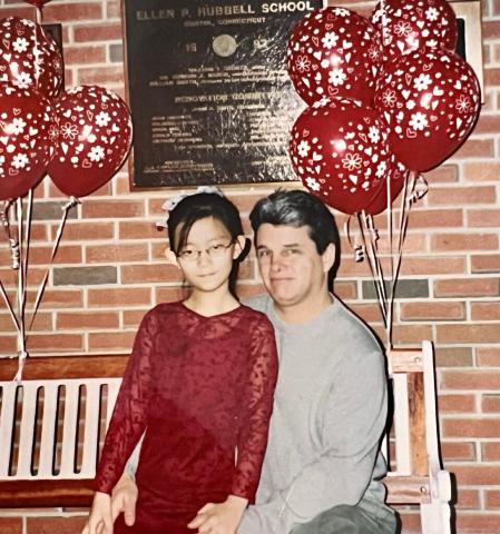 Adult and child pose in front of balloons