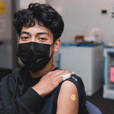 A teen shows off where they got their COVID vaccine