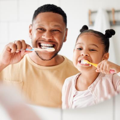 Father and daughter brushing teeth together.