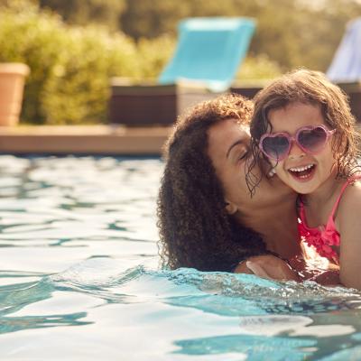 Mom and young daughter swimming in pool. Mom holding daughter.